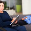 portrait of middle aged female therapist in office with patient in background