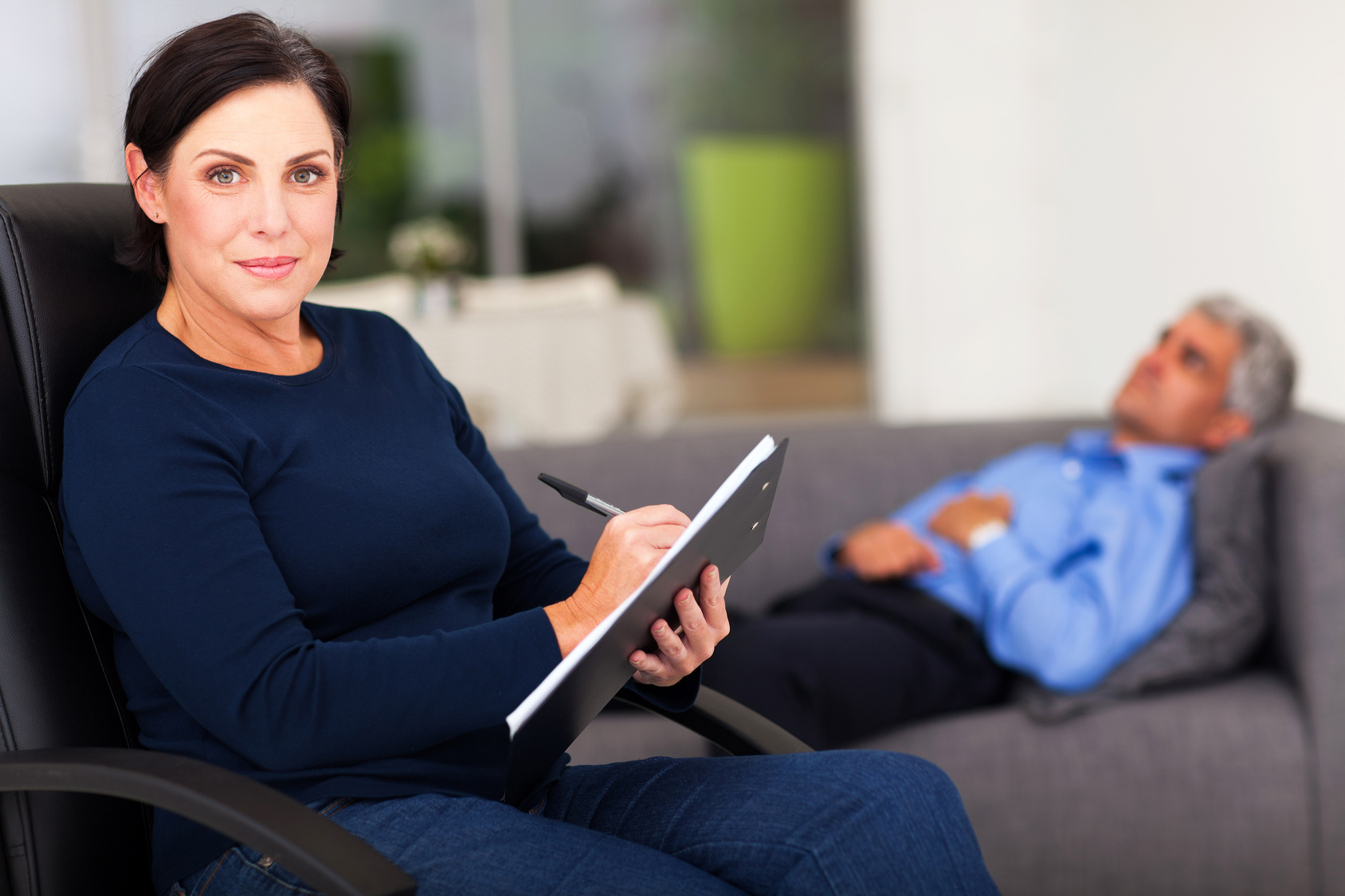 portrait of middle aged female therapist in office with patient in background